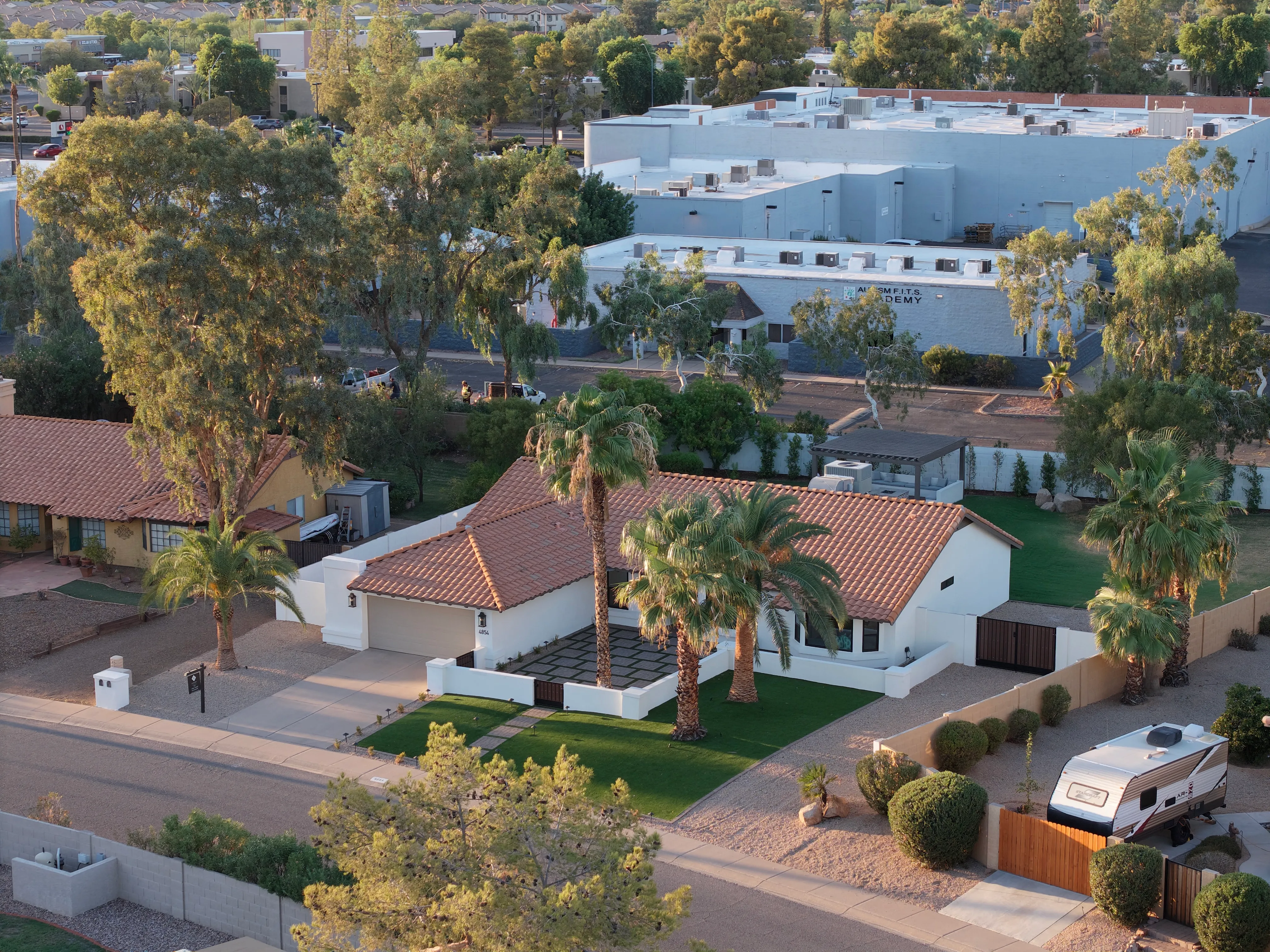 Aerial photograph of a single-story home at golden hour, showing the lot, roofline and surrounding neighborhood