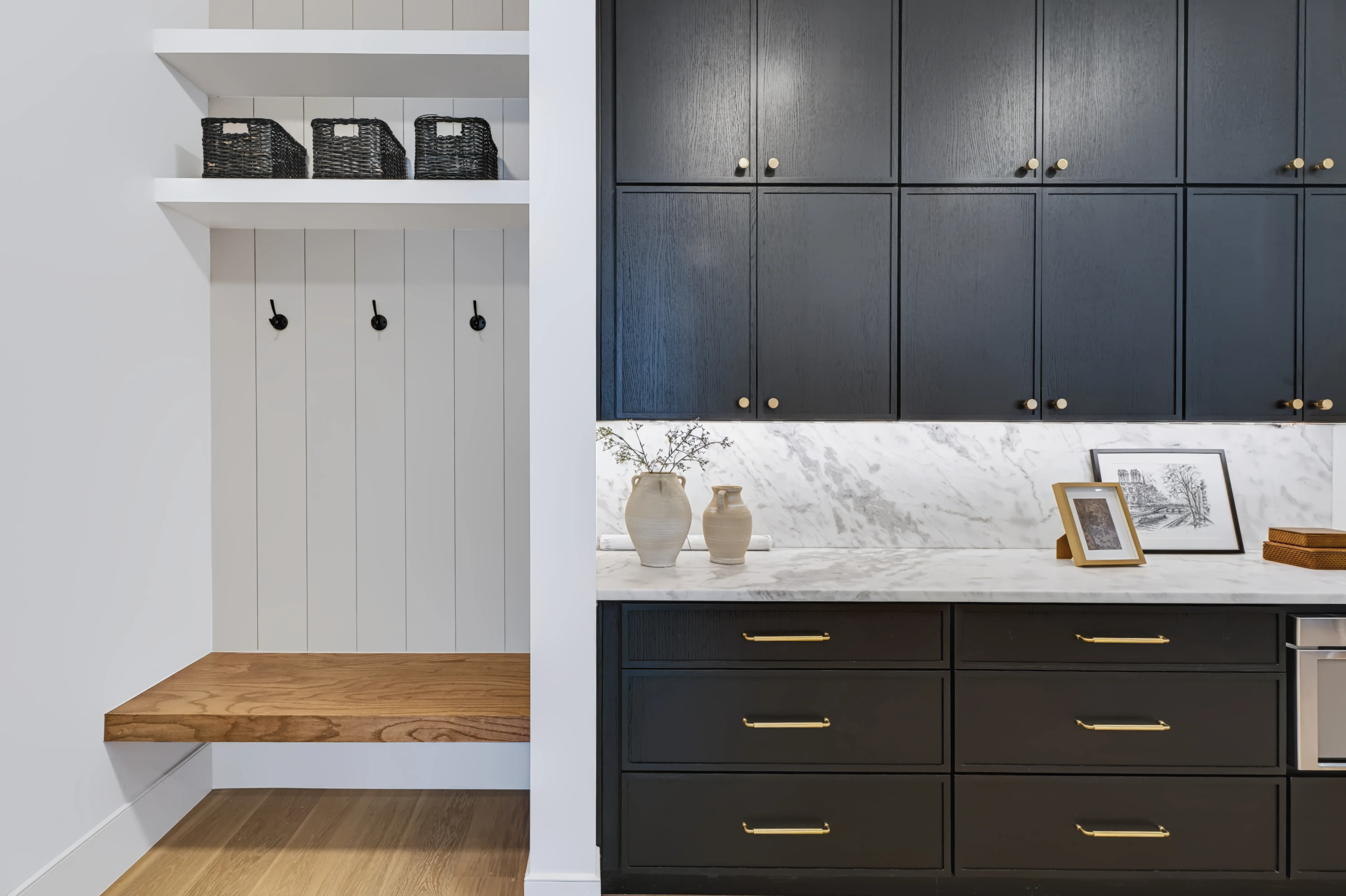 Scullery and drop zone with black-oak cabinetry, a marble counter and a floating oak bench under coat hooks