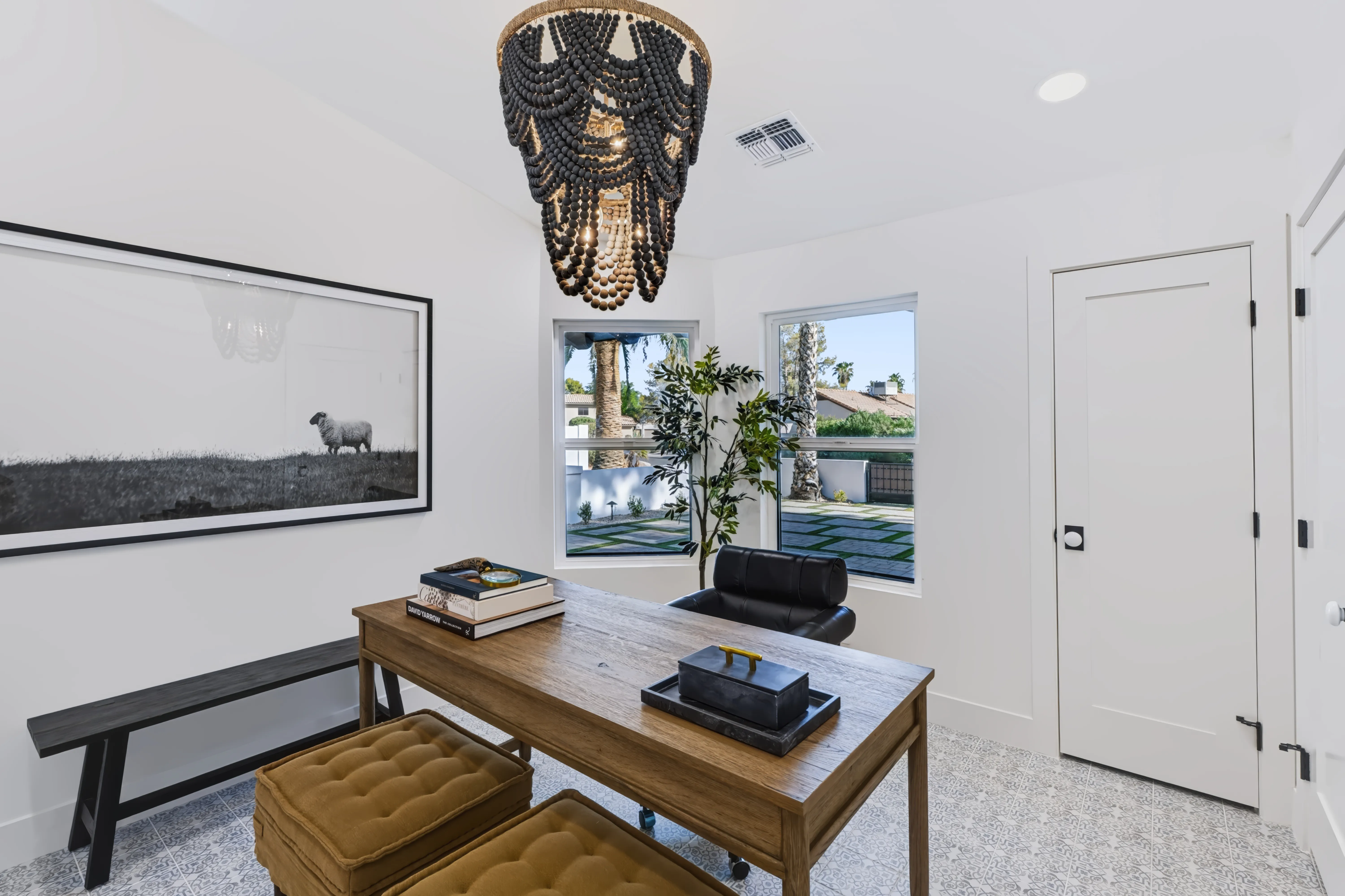 Study with a black wood-bead chandelier, an oversized black-and-white sheep photograph and a light oak desk