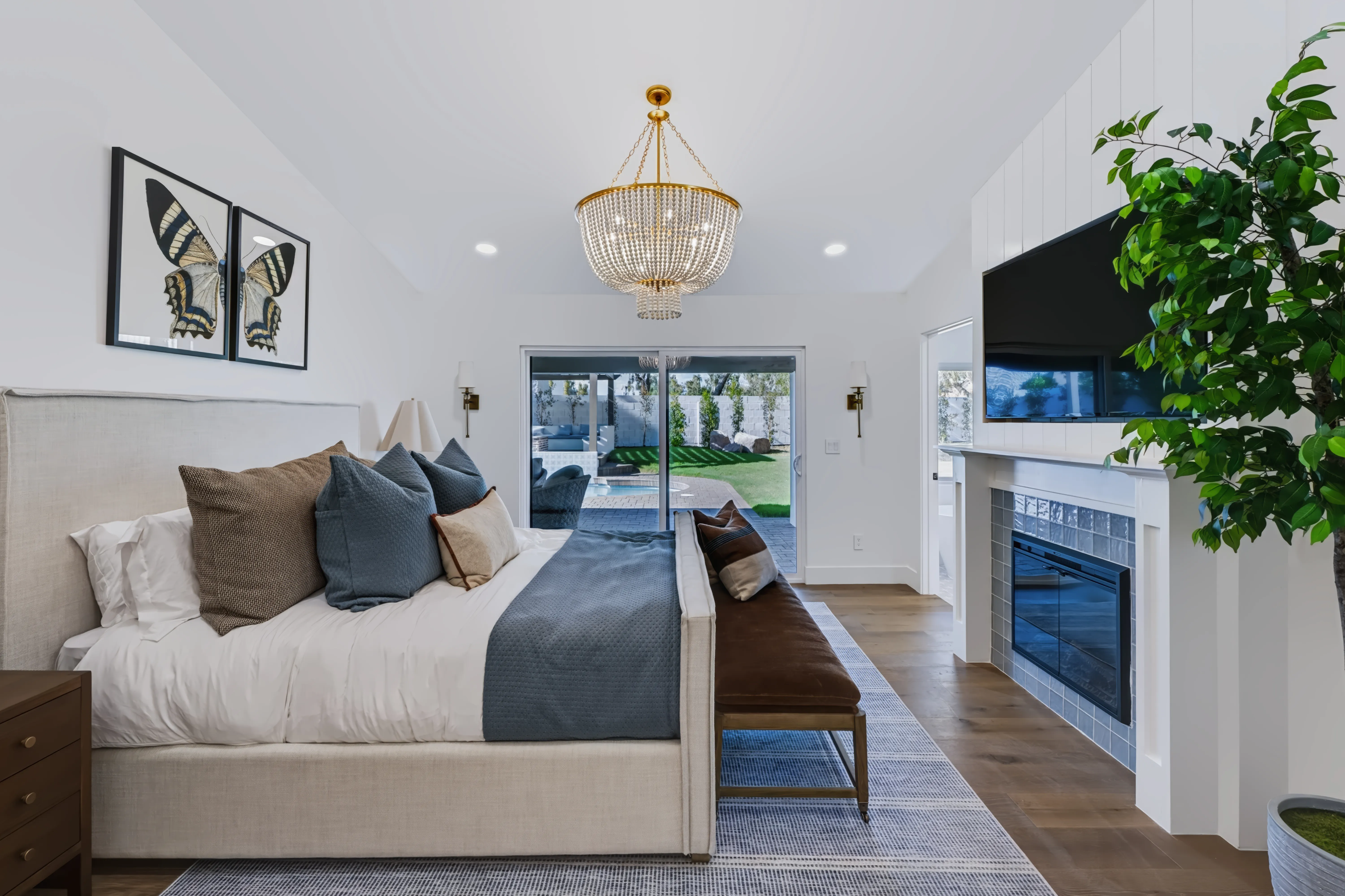 Primary bedroom with a tiled gas fireplace, a beaded chandelier and sliding glass to the pool