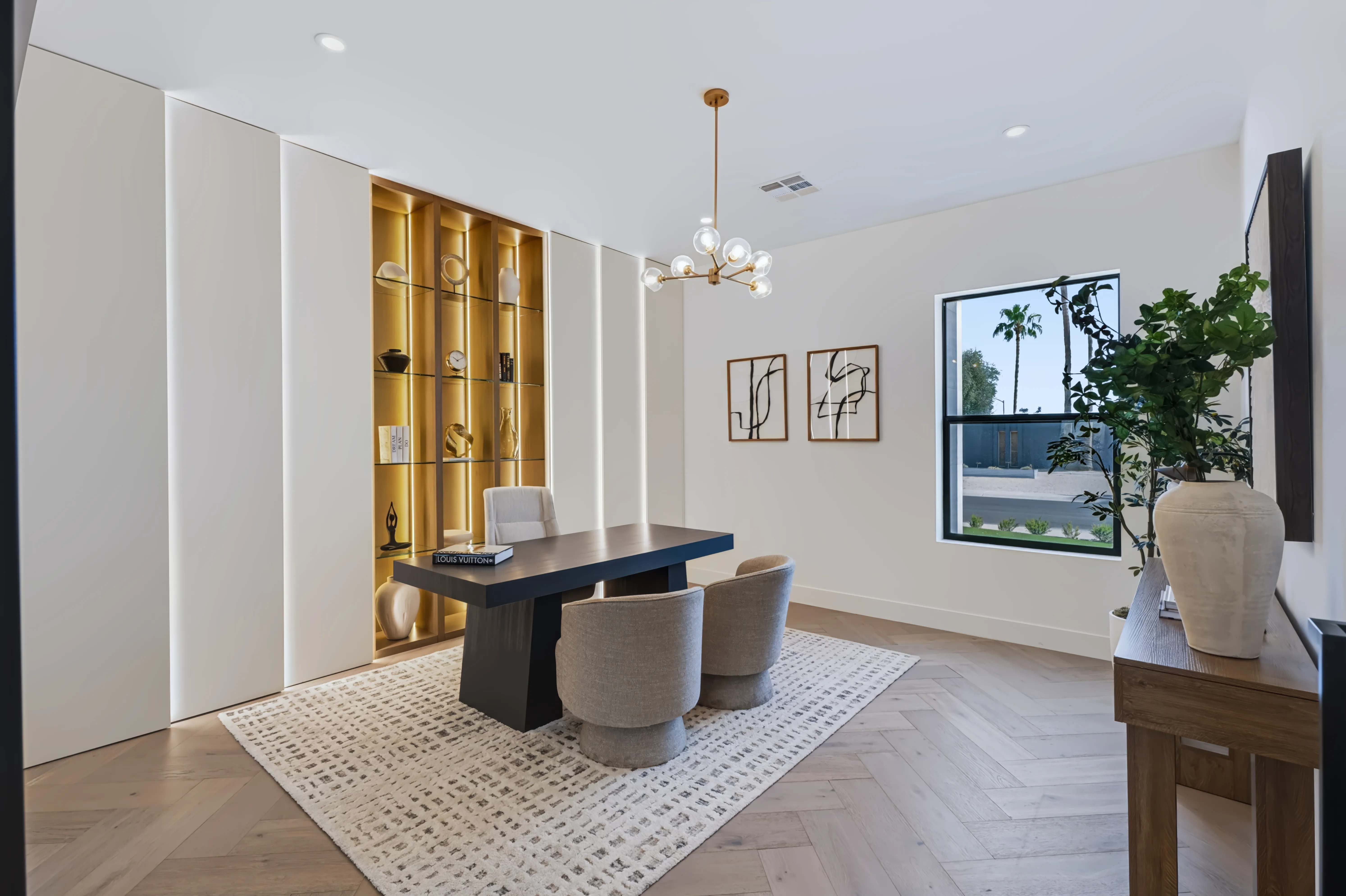 Study with a dark wood desk on a patterned rug, backlit glass shelving, and a window onto the front garden