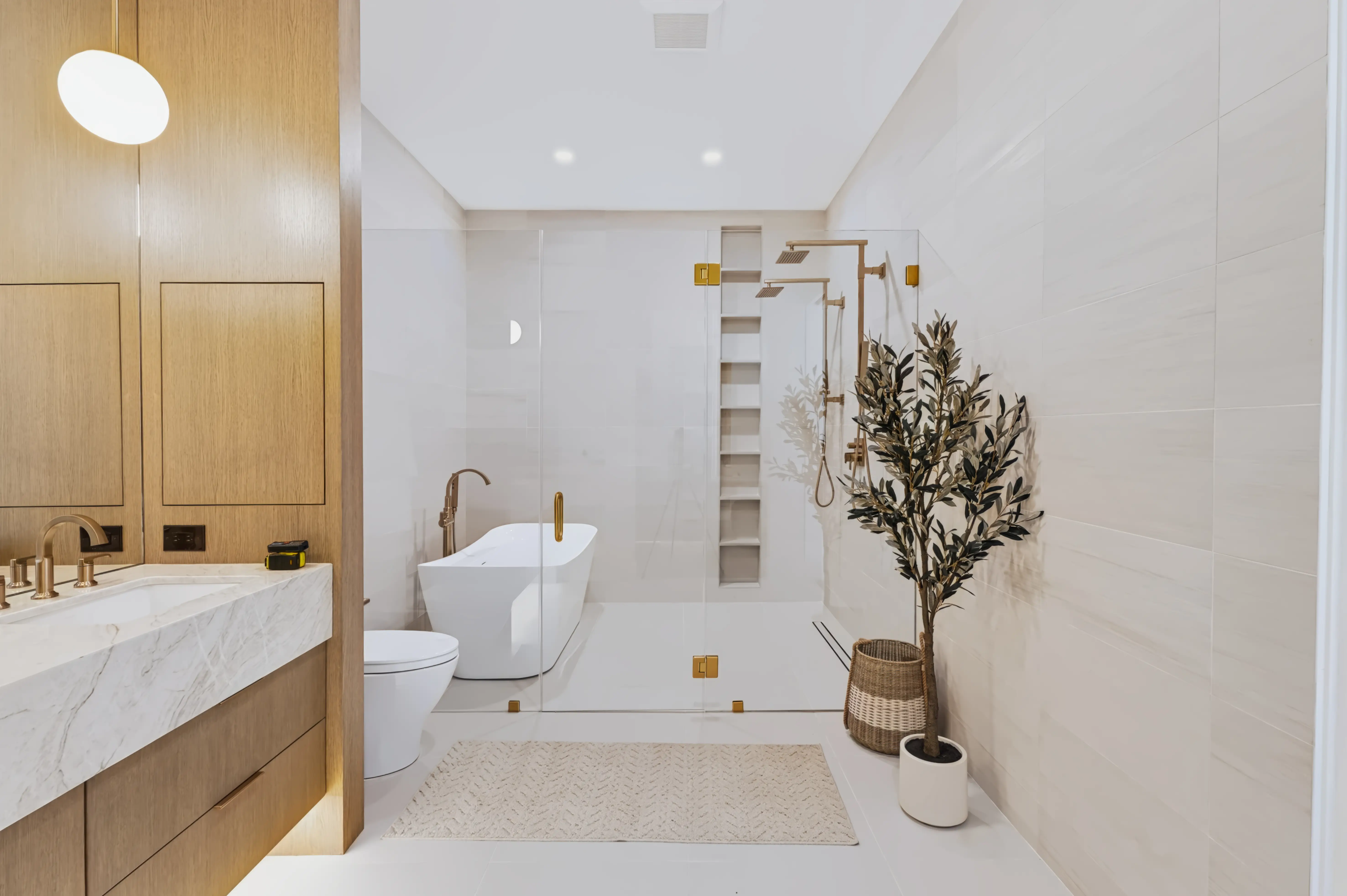 Primary bath with a freestanding tub, a glass shower with dual brass heads and a marble-topped oak vanity