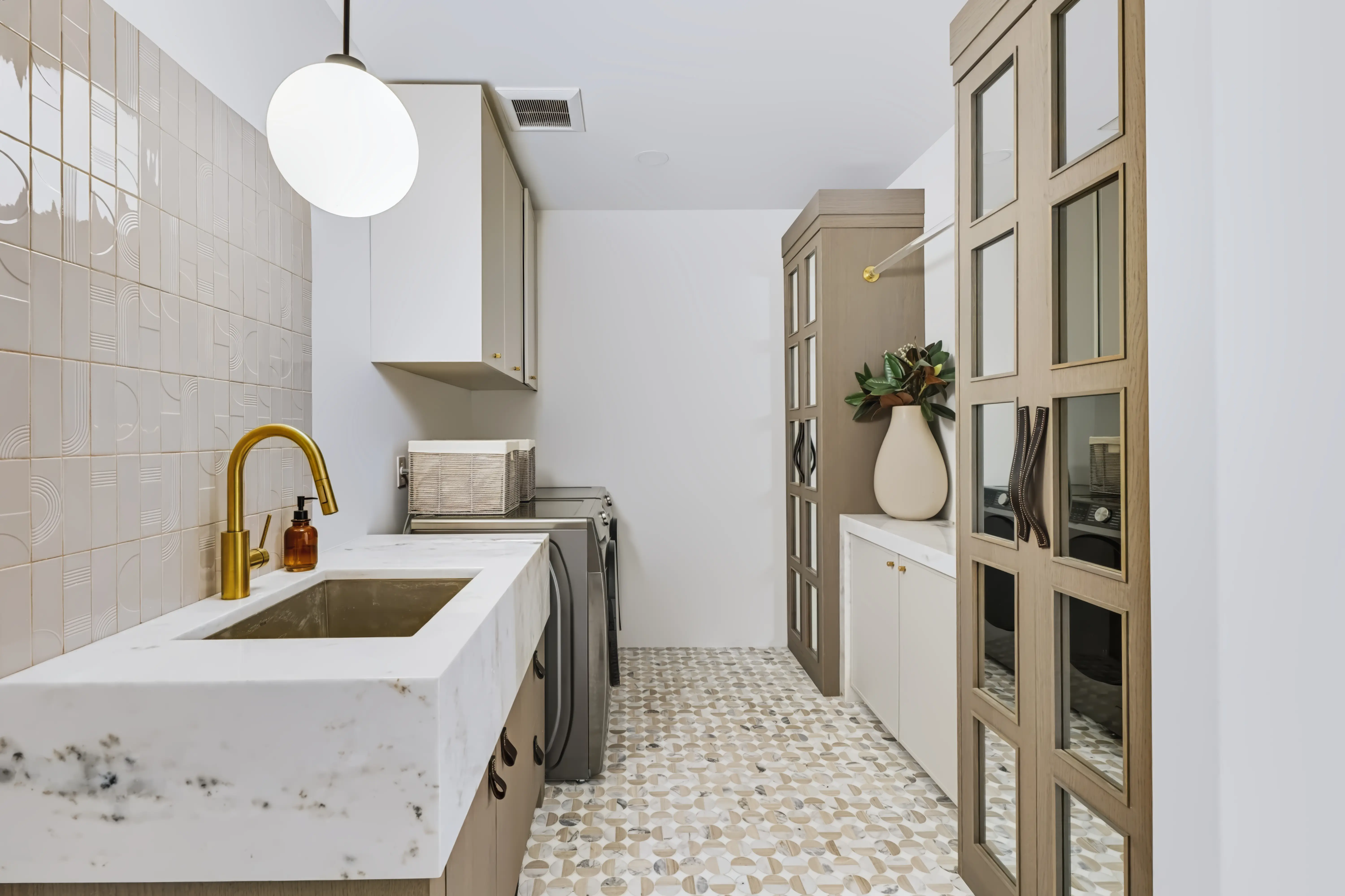 Laundry room with a carved marble trough sink, brass tap and a penny-round mosaic floor