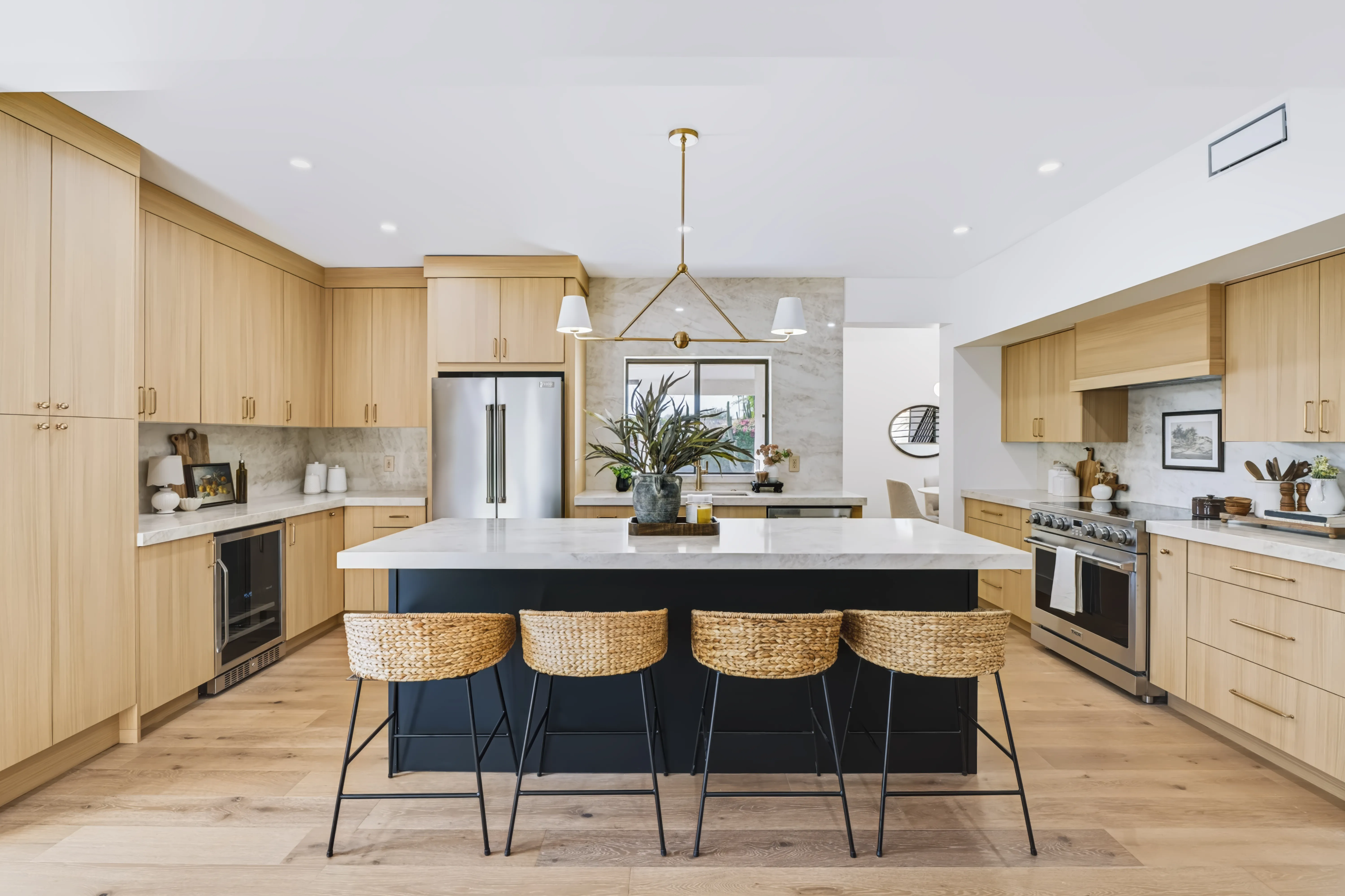 A close view of a kitchen island's marble waterfall edge and woven counter stools