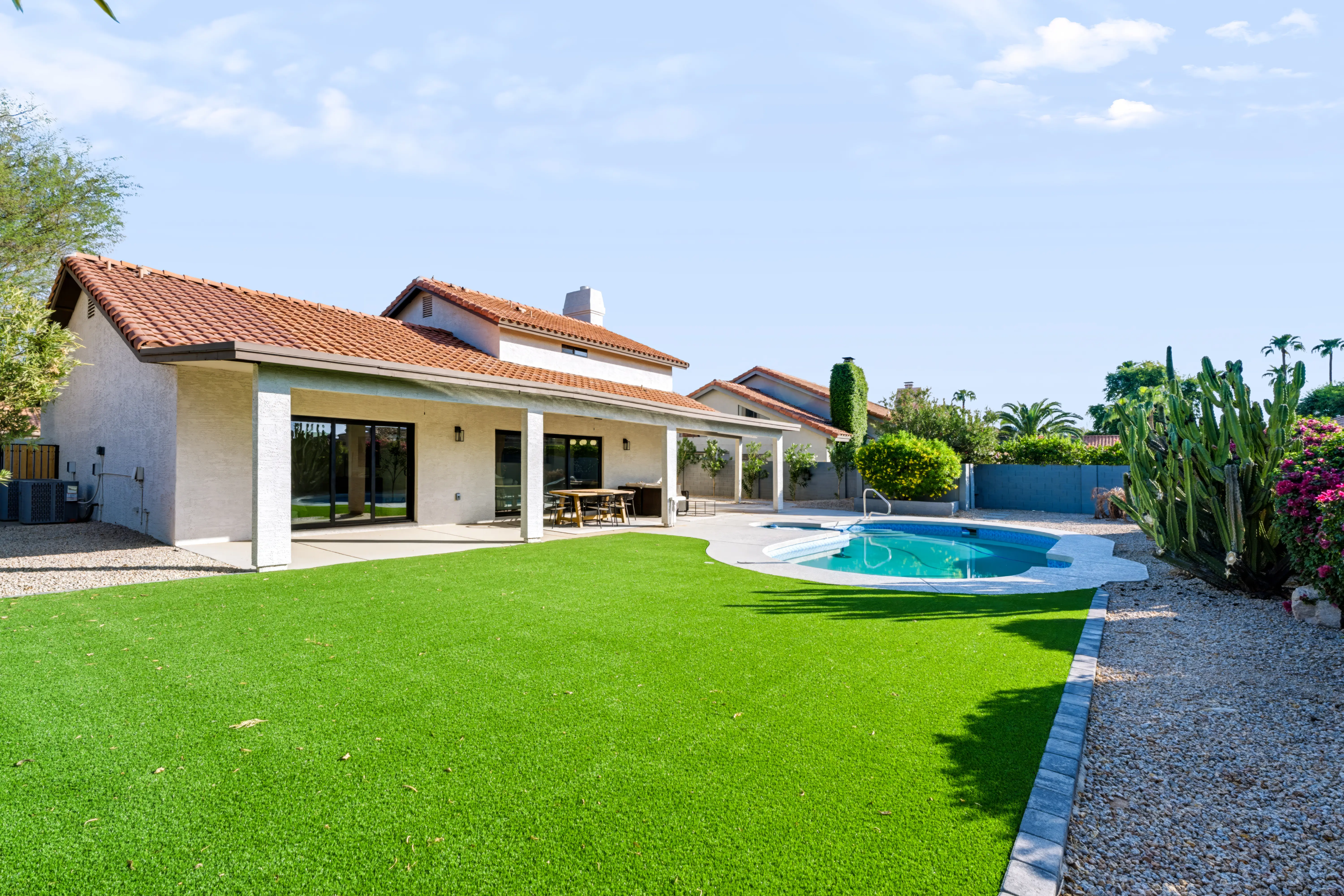 Backyard exterior with an artificial-turf lawn, a kidney-shaped pool and the tile-roofed elevation behind