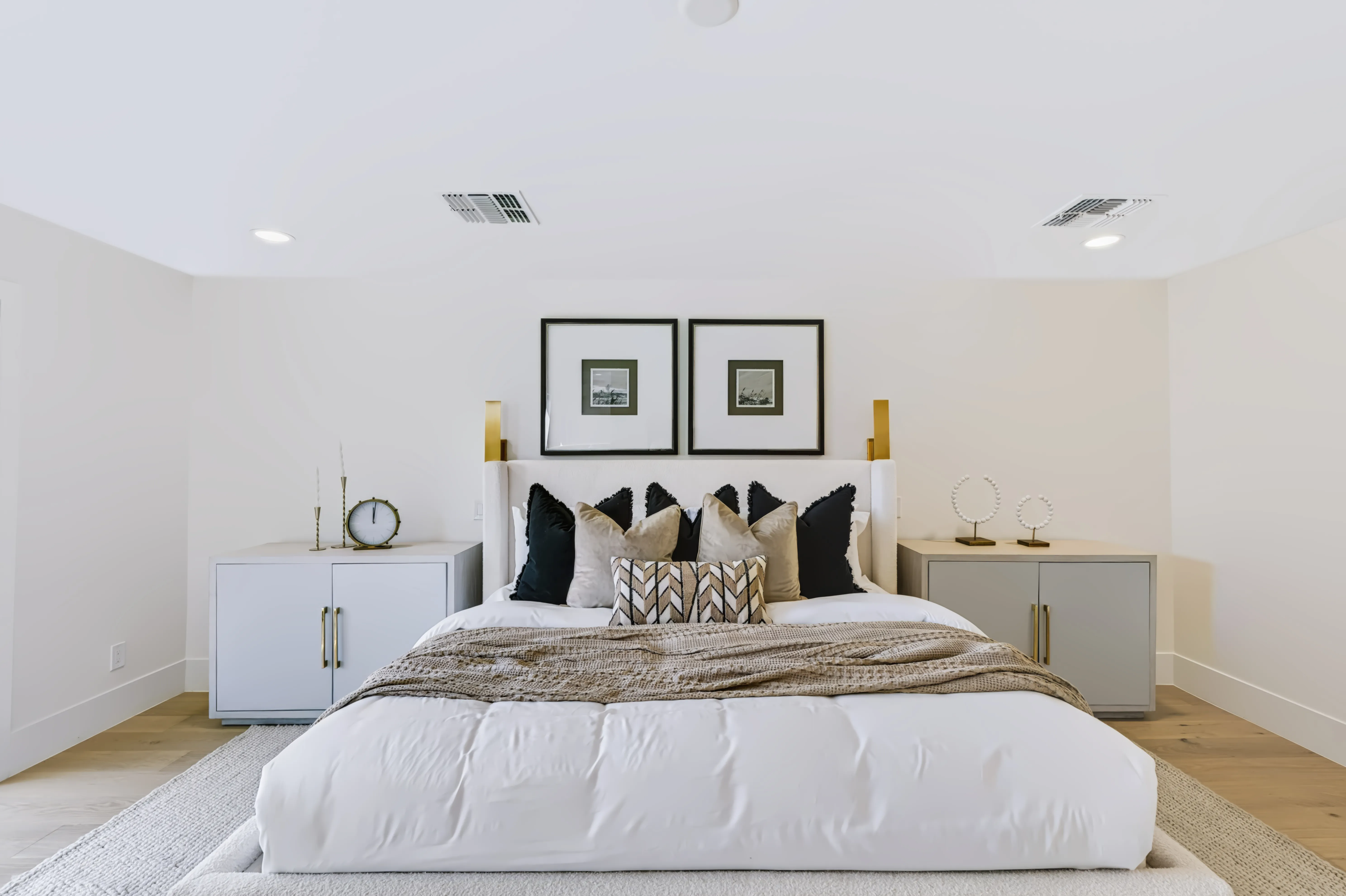 Primary bedroom straight on, a pair of framed prints over the headboard between matching grey nightstands