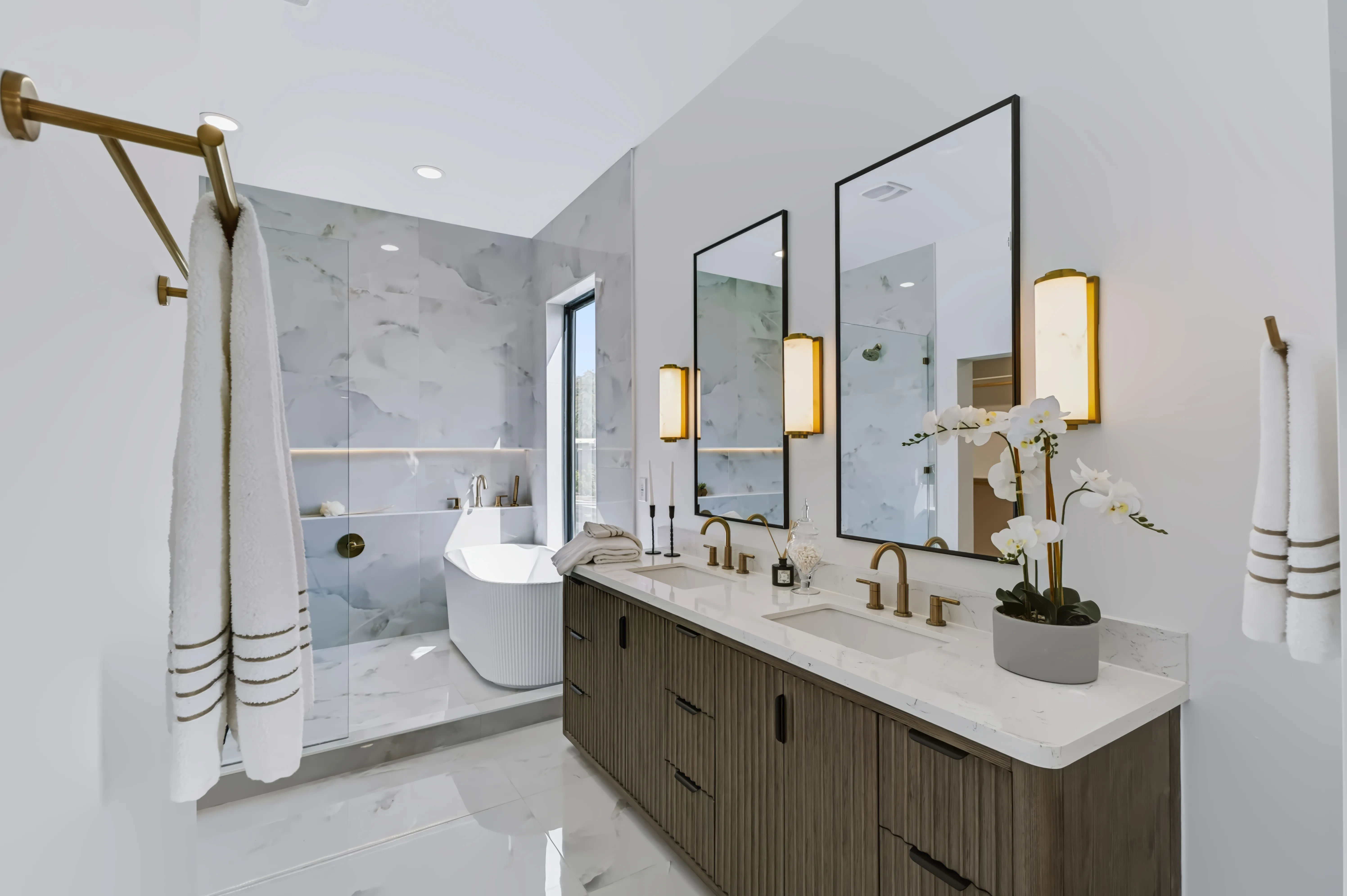 Primary bath from the doorway, twin mirrors and an orchid on the marble counter with the freestanding tub beyond